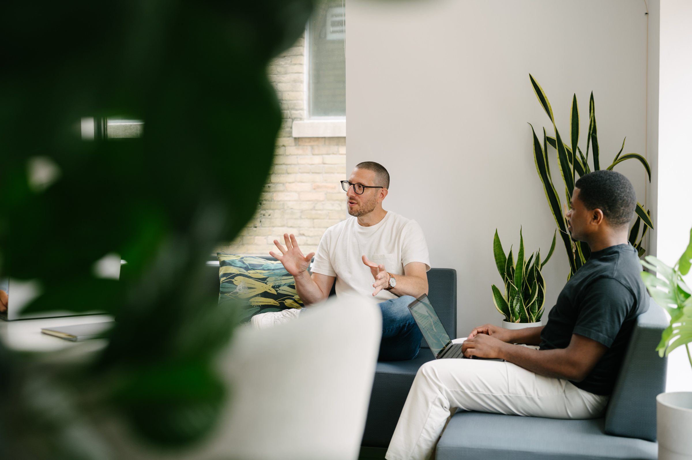 Jason Goodman in a working session with a founder, seen through the plants